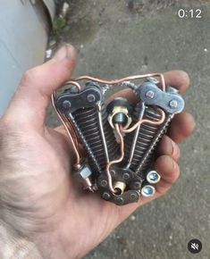 a hand holding an old motorcycle engine in it's right hand