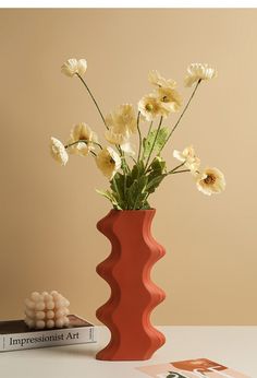 there is a vase with flowers in it next to two books and a book on the table