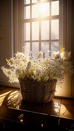 a basket filled with white flowers sitting on top of a wooden table next to a window