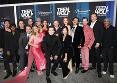 a group of people standing next to each other in front of a wall with the words teen wolf on it