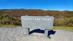 a sign that is sitting on the side of a hill with mountains in the background