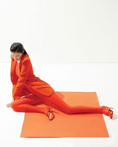 a woman sitting on an orange mat with her legs crossed