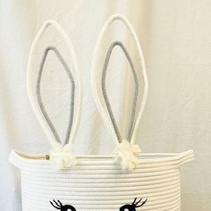 a white basket with two bunny ears on the front and one has eyes painted on it