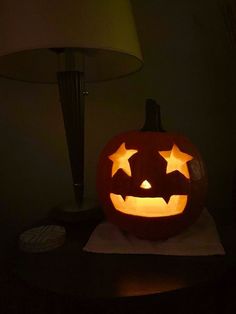 a carved pumpkin sitting on top of a table next to a lamp and paper towel