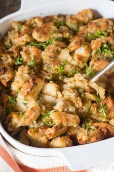 a casserole dish filled with stuffing and garnished with fresh parsley