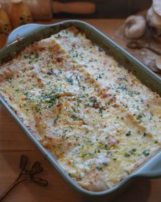 a casserole dish with cheese and herbs in it sitting on a table next to mushrooms