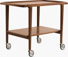 a wooden table with wheels and a shelf on the top that is holding a tray