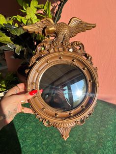 a person holding up a mirror with an eagle on it