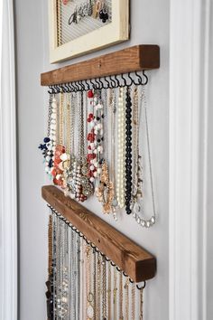 a wall mounted jewelry rack with several necklaces hanging from it's sides and two framed pictures on the wall