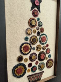 a christmas tree made out of buttons on a white wall with a wooden framed frame