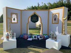 an outdoor stage set up with pillows and other decorative items on the ground in front of it