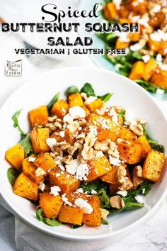 a white bowl filled with roasted butternut squash salad and topped with feta cheese