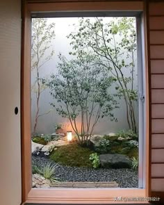 an open window shows a small garden with rocks and trees in the foreground, lit by a candle