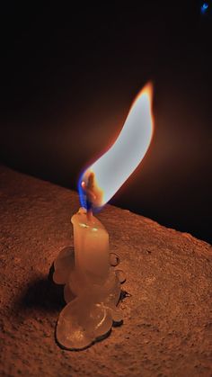 a lit candle sitting on top of a rock