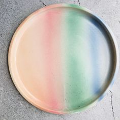 a multicolored plate sitting on top of a cement floor next to a wall