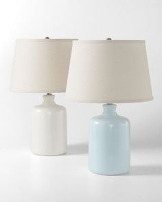 two white and light blue lamps on a table with one lamp turned off to the side