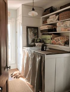 an open closet with clothes hanging on the shelves and baskets in front of it, next to a door