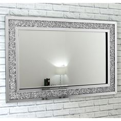 a white brick wall with a large mirror on the side and a lamp next to it