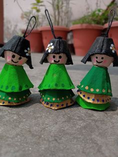 three small wooden dolls are dressed in green