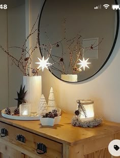 a wooden table topped with two white vases filled with christmas decorations