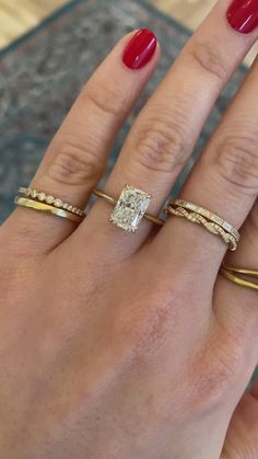 a woman's hand with three different rings on her fingers and one ring in the middle