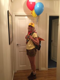 a girl is standing in the hallway with balloons on her head and holding a skateboard