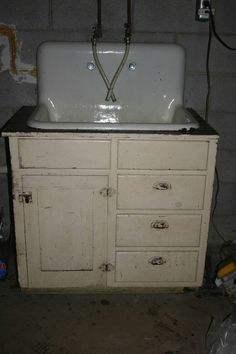 an old white sink sitting on top of a wooden cabinet