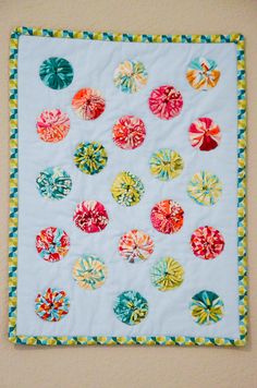 a quilted wall hanging on the side of a wall with many different colored buttons