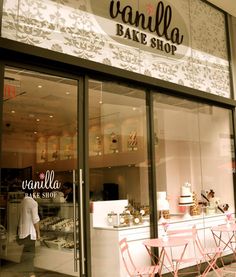 a store front with pink chairs and cakes on display