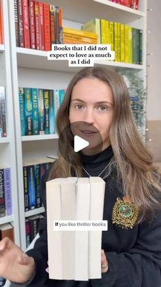 a woman holding up a book in front of bookshelves with a fake moustache on her face