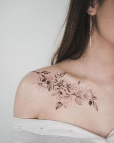 a woman's shoulder with flowers and leaves tattoo on her left side breast piece