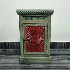 a green cabinet with a red design on the front and side door, sitting on top of a tile floor