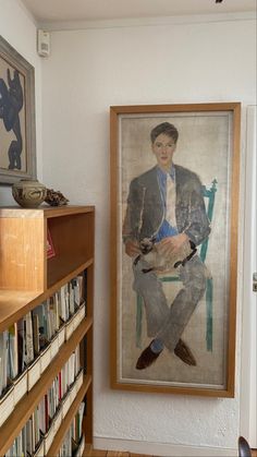 a portrait of a man sitting in a chair next to a bookshelf filled with books