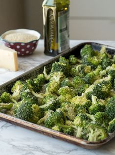 broccoli florets in a baking pan with cheese and seasoning on the side