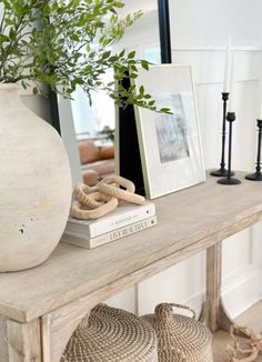 a white vase sitting on top of a wooden table next to two baskets filled with plants