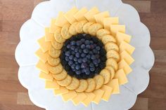 a cheese and cracker cake with blueberries in the center on a white plate