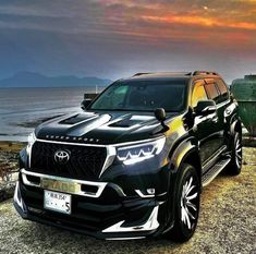 a black suv parked next to the ocean