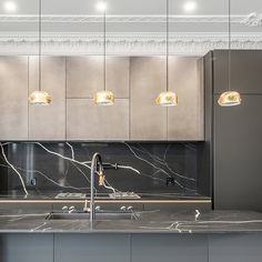 a kitchen with marble counter tops and gold lighting fixtures on the ceiling, along with stainless steel appliances