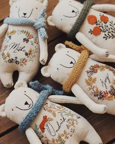 four white bears with hats and scarves on them are sitting on a wooden table