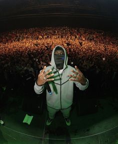 a masked man standing in front of an audience at a concert with his hands out