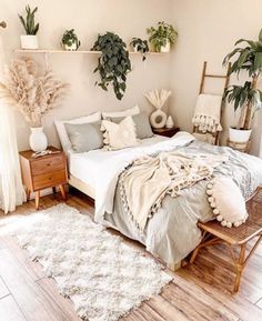 a bed sitting in a bedroom next to two potted plants