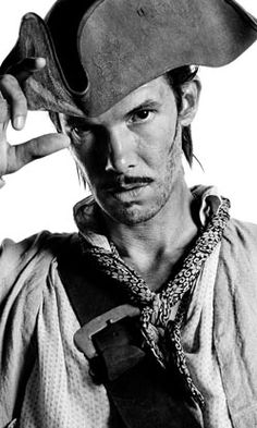 a man wearing a pirate hat and holding a cell phone to his ear while standing in front of a white background