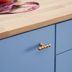 a wooden counter top sitting next to a blue cabinet with gold knobs on it