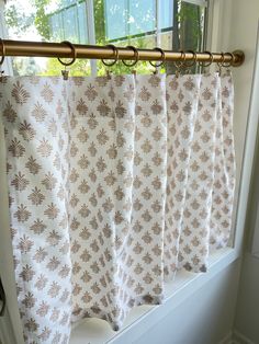 the curtains are hanging on the rod in front of the window sill, which is decorated with brown and white flowers