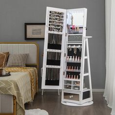 a bedroom with a bed, mirror and jewelry rack on the floor in front of it