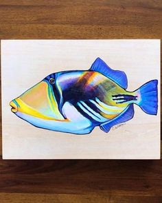 a blue and yellow fish on a wooden surface