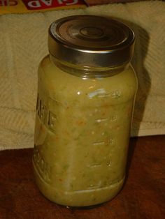 a jar filled with green liquid sitting on top of a wooden table