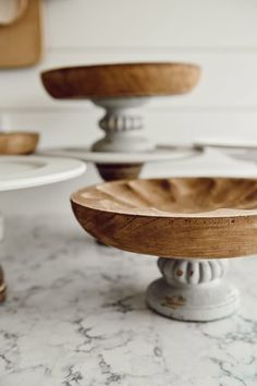 three wooden bowls sitting on top of a marble counter next to other plates and utensils