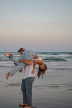 a man carrying a woman on his back at the beach