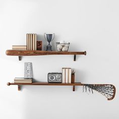 two wooden shelves with books, vases and other items on them against a white wall